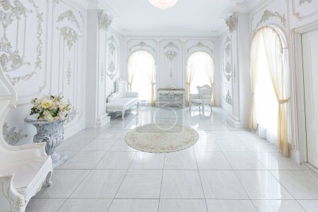 luxuriöses, nobles Interieur im Barockstil. sehr helle, helle und weiße Halle mit teuren Möbeln im alten Stil. große Fenster und Stuckverzierungen an den Wänden