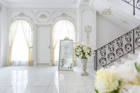 Photo for Luxury royal posh interior in baroque style. very bright, light and white hall with expensive oldstyle furniture. chic wide marble staircase leading to the second floor - Royalty Free Image