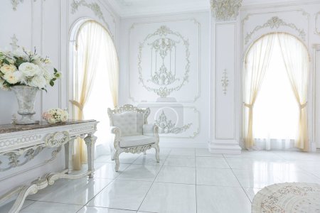 luxury royal posh interior in baroque style. very bright, light and white hall with expensive oldstyle furniture. large windows and stucco ornament decorations on the walls