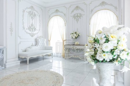 interior elegante real de lujo en estilo barroco. vestíbulo muy luminoso, ligero y blanco con muebles de estilo antiguo caros. grandes ventanas y adornos de estuco en las paredes