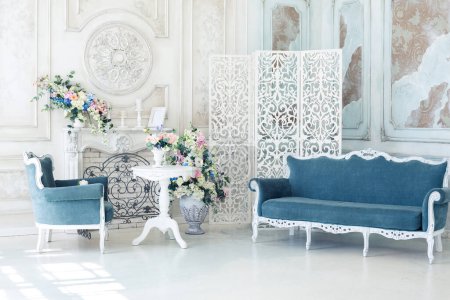 Photo for Bright luxury white and blue colored interior living room with flowers in vases. the walls are decorated with baroque ornaments - Royalty Free Image