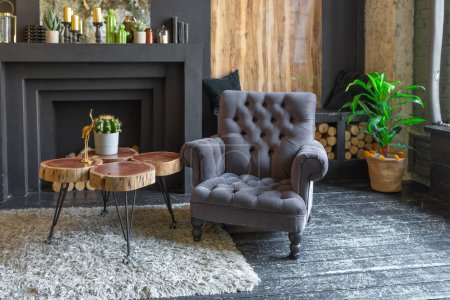 Photo for Dark brutal interior of sitting room decorated with wooden logs. yellow and grey soft armchairs, huge arc window and fireplace - Royalty Free Image