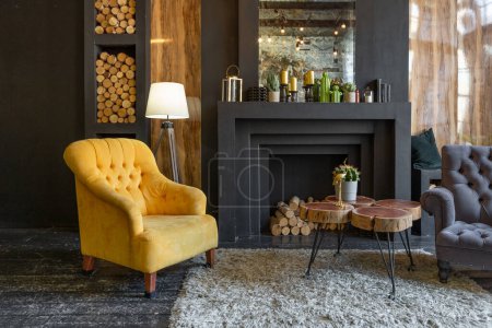 Foto de Oscuro interior brutal de la sala de estar decorada con troncos de madera. sillones suaves amarillos y grises, gran ventana de arco y chimenea - Imagen libre de derechos