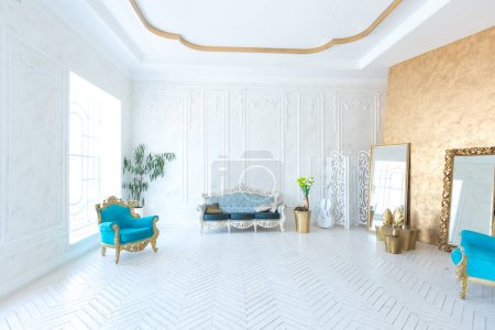 Foto de Interior luminoso de lujo de la sala de estar con pared de oro y muebles caros elegantes en colores blanco y oro - Imagen libre de derechos