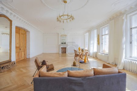 Photo for Luxury interior of a spacious apartment in an old 19th century historical house with modern furniture. high ceiling and walls are decorated with stucco - Royalty Free Image