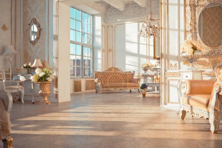 Photo for Rich apartment interior with golden baroque decorations on the walls and luxury furniture. the room is flooded with the rays of the setting sun - Royalty Free Image