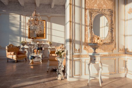riche appartement intérieur avec des décorations baroques dorées sur les murs et des meubles de luxe. la pièce est inondée des rayons du soleil couchant