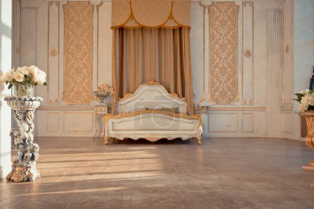 Foto de Rico interior del apartamento con decoraciones barrocas doradas en las paredes y muebles de lujo. la habitación está inundada con los rayos del sol poniente - Imagen libre de derechos