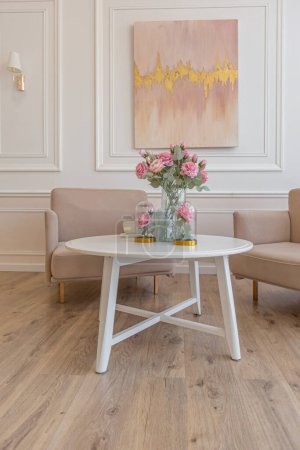 ein naher Blick auf einen Teetisch mit zwei stilvollen Sesseln in einem modernen gemütlich weichen Interieur in warmen zarten Pastellrosa und Beige-Farben