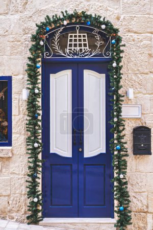 Téléchargez les photos : Porte d'entrée bleue marine de la maison résidentielle décorée pour les vacances de Noël avec des couronnes et des guirlandes - en image libre de droit
