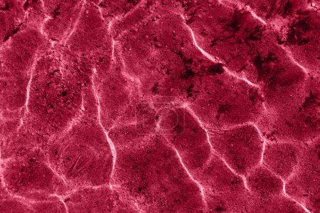 Abstraktes Muster Meerwasser ätzende Textur Hintergrund mit Muster von Wellen und Sonnenreflexion. Bild getönt in Farbe des Jahres 2023 viva magenta