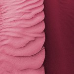 Waves of sandy dunes surface. Close-up of dune sand beach in summer. Toned by trendy color of the 2023 year Viva Magenta