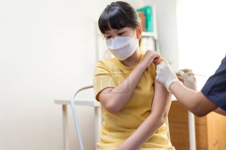 Téléchargez les photos : Asiatique adolescent fille dans hôpital masque pendant vaccination coronavirus concept - en image libre de droit