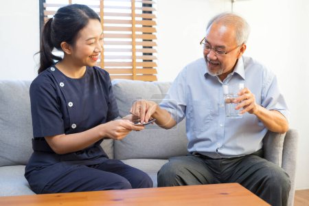 Foto de Enfermera sonriente dando medicina a hombre asiático mayor en asilo de ancianos o centro de vida asistida - Imagen libre de derechos