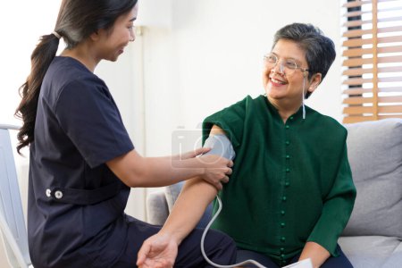 Photo for Asian woman doctor measuring blood pressure of mature woman in hospital - Royalty Free Image