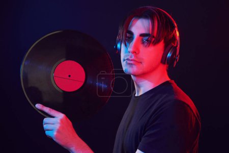 Foto de With vinyl record in hands. Man standing in the studio with neon light. - Imagen libre de derechos