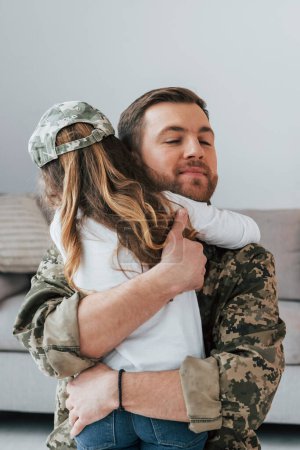Foto de Abrazándose mutuamente. Soldado de uniforme está en casa con su hijita. - Imagen libre de derechos