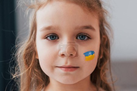 Photo for Close up view. Portrait of little girl with Ukrainian flag make up on the face. - Royalty Free Image