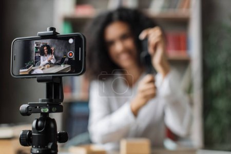 Photo for Focus on smart phone screen, african american woman doing live stream while unpacking box with new smart watch. Female blogger sharing her feedback about modern gadget with her subscribers. - Royalty Free Image