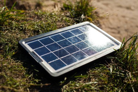 Foto de Tecnologías modernas de energía portátil. El panel solar se encuentra en la hierba bajo los cálidos y suaves rayos del sol. Una hermosa foto de un panel solar para cargar teléfonos. - Imagen libre de derechos