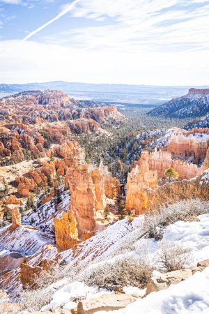 Téléchargez les photos : Bryce Canyon accented in freshly fallen snow and distant mountains and brilliantly colored orange cliffs. - en image libre de droit