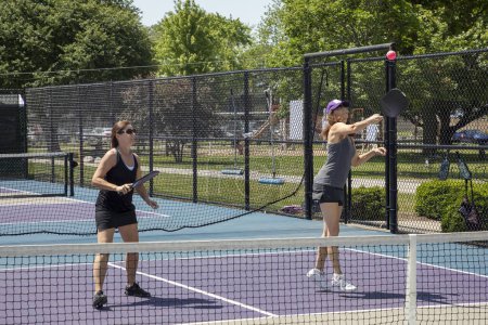Two pickleball players in action on a suburban pickleball court during summer.