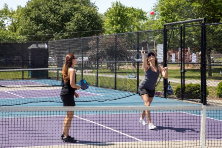 Two pickleball players in action on a suburban pickleball court during summer.