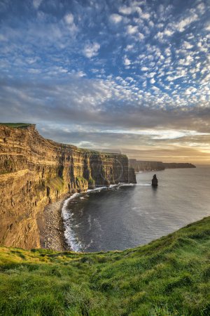 Photo for Sunshine illuminates the coastline along the Cliffs of Moher just before sunset in the Burren region in County Clare, Ireland. - Royalty Free Image
