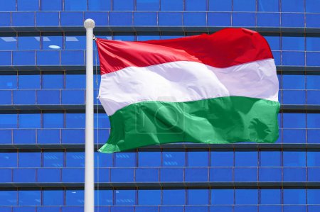 Im Wind weht die ungarische Flagge vor dem Hintergrund eines modernen Gebäudes. Konzept von Politik, Wirtschaft und Tourismus in Ungarn