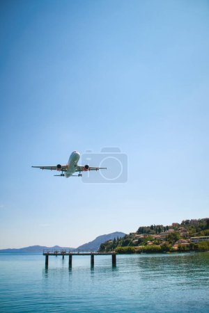 Foto de Un avión que se acerca a la ciudad de Corfú, cerca de las hermosas aguas azules del mar - Imagen libre de derechos