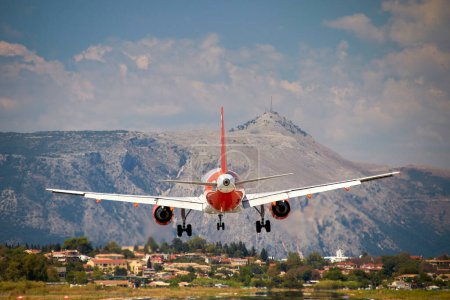 Foto de Prepararse para aterrizar, naranja avión blanco rojo por detrás justo antes de aterrizar en la pista del aeropuerto de Corfú, Grecia - Imagen libre de derechos