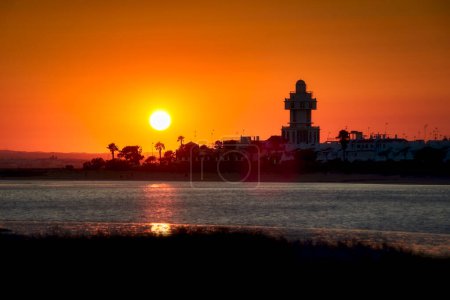 Photo for Beautiful orange sunset panorama at the harbor of Isla Cristina, Costa de la Luz, Spain, with the lighthouse as a silhouette - Royalty Free Image