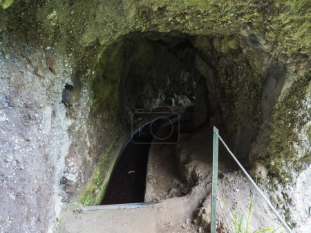 Vista a través del túnel de Levada Do Rei, canal de riego de agua y caminata PR18, desde Sao Jorge terminando en la fuente en Ribeiro Bonito, Madeira, Portugal.