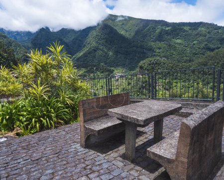banco de hormigón y mesa con hermosa vista sobre colinas verdes y valle desde el lugar de descanso, mirador en Sao Roque do Faial Santana, Isla de Madeira, costa norte