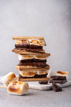 Freshly roasted smores with large white marshmallows. Delicious marshmallow sandwich with cracker and chocolate on grey table, closeup. 