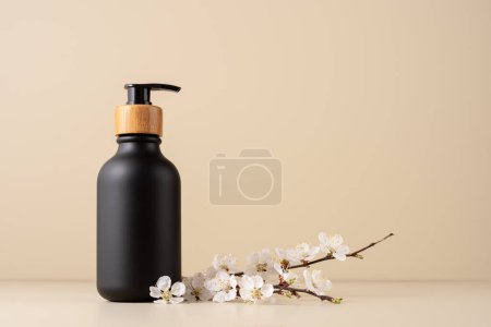 Black dispenser bottle for cosmetic and bath product mock-up with cherry blossom twig