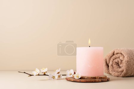 Téléchargez les photos : Bougie ardente répandant l'arôme sur la table dans une salle de spa. Belle composition avec bougie de couleur pastel et perruque de fleur de cerisier pour le traitement spa, printemps. - en image libre de droit