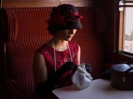 Attractive 1920s woman  in red flapper dress and cloche hat posing in the 1927 first class interior of an authentic steam train