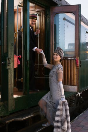 Téléchargez les photos : Lady in 1920s flapper dress costume entering the first class carriage of an authentic 1927 steam train - en image libre de droit
