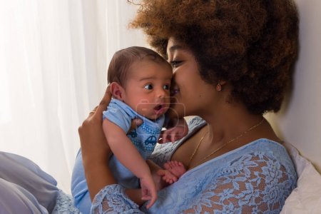 Téléchargez les photos : Belle jeune mère africaine dans une robe en dentelle bleue collant avec son nouveau-né de seulement 11 jours - en image libre de droit