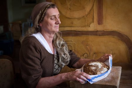 Mujer con traje auténtico de campesino renacentista sosteniendo pan.