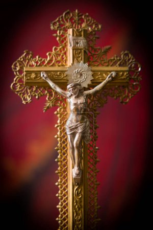 Téléchargez les photos : Crucifix antique en bois et filigran d'or debout devant un rideau de velours rouge - en image libre de droit
