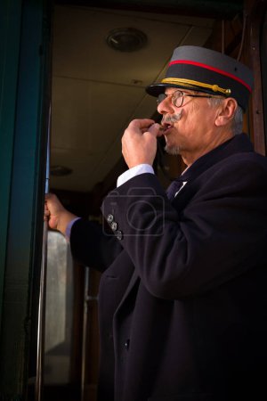 Photo for Reenactment scene with authentic 1927 1st class train carriage and a retro train conductor at departure - Royalty Free Image