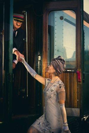 Téléchargez les photos : Lady in 1920s flapper dress costume entering the first class carriage of an authentic 1927 steam train - en image libre de droit