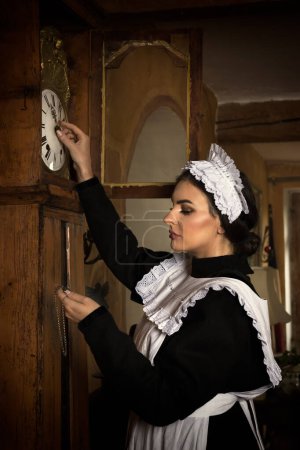Foto de Escenas de una hermosa joven criada victoriana haciendo tareas domésticas en un interior antiguo - Imagen libre de derechos