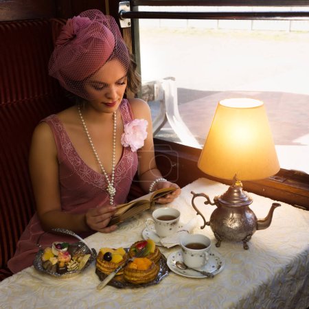 Foto de Escena de recreación de una dama vestido flapper de 1920 disfrutando de té alto en un auténtico compartimiento de tren de vapor 1927 - Imagen libre de derechos