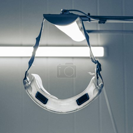 Photo for Protective goggles for the eyes hanging on the luminaire in a hazardous production facility - Royalty Free Image
