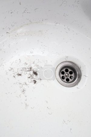 shaved hair from the intimate areas of the pubic area after shaving and depilation remaining on the walls of the bathroom sink, close-up texture