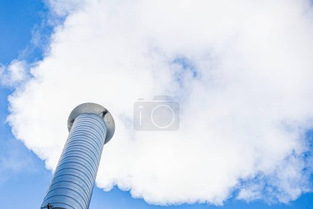 Photo for Metal chimney of a geothermal power station with stainless steel pipe structure with smoke and steam - Royalty Free Image