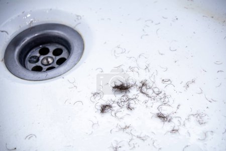 cabello afeitado de las zonas íntimas de la zona púbica después del afeitado y depilación restante en las paredes del lavabo del baño, textura de primer plano
